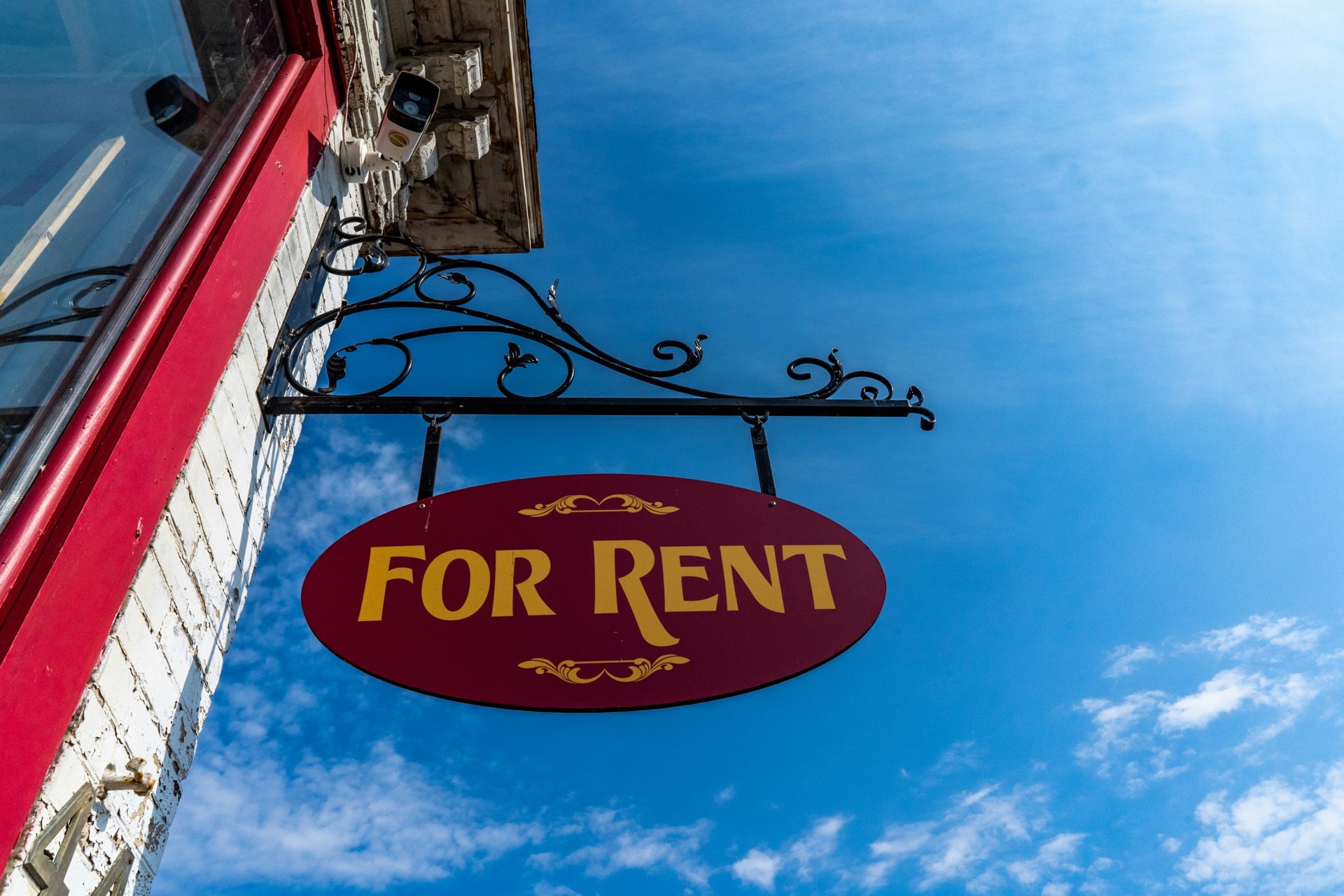 Hanging For Rent sign against a blue sky