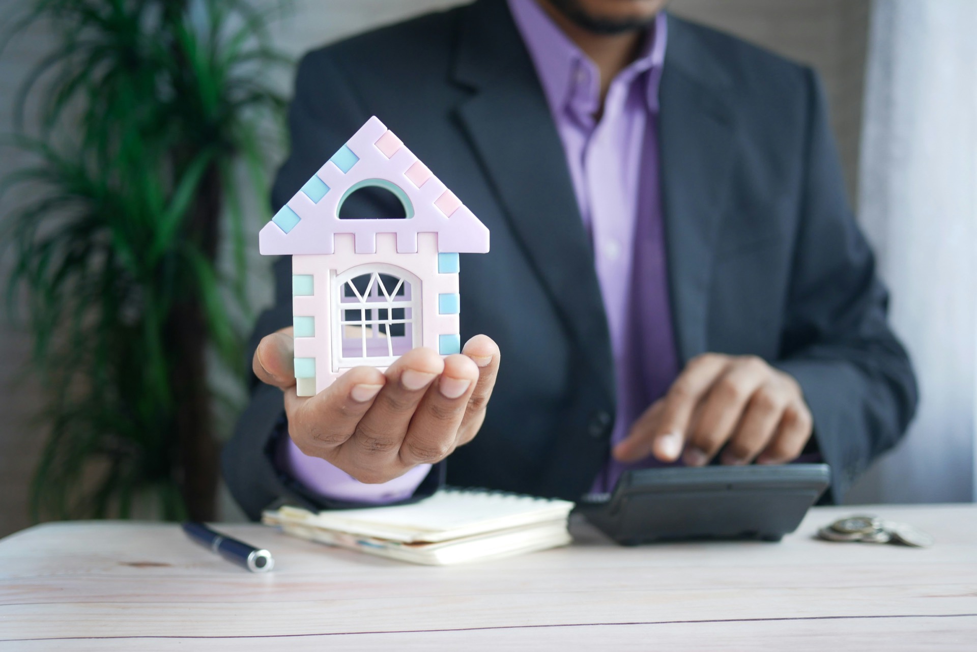 Consultant holding a model house while reviewing costs